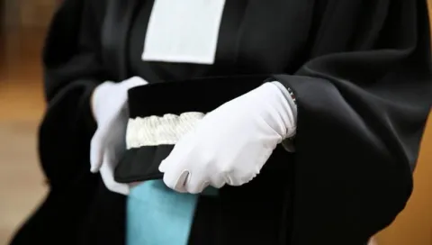 Mains gantées et mortier de magistrat judiciaire